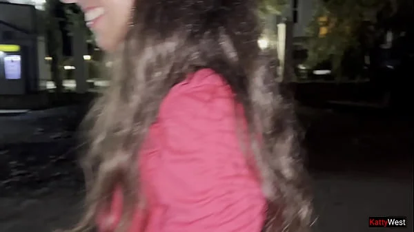 Two girlfriends pee together near a car in a public parking lot